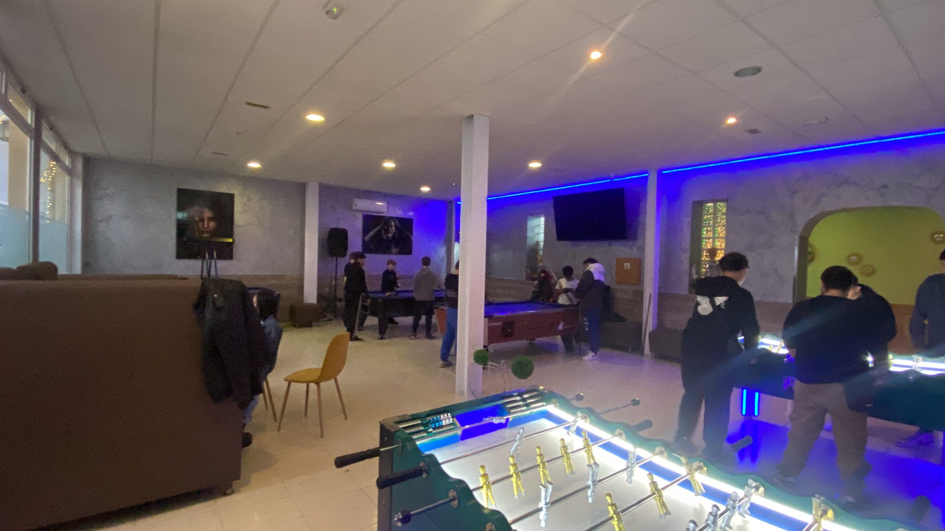 Sala de juegos del Bar Buen Rollo con mesas de billar y futbolines iluminados
